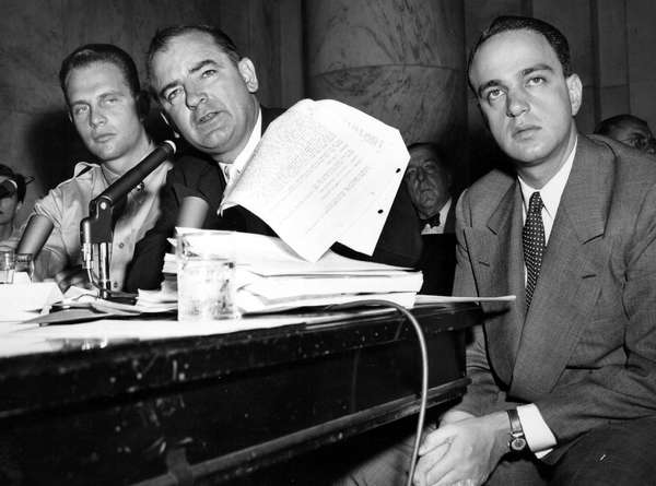 Senator Joseph McCarthy waves a transcript of a monitored call between Pvt. G. David Schine (left) & Secretary of the Army Stevens, Army-McCarthy hearings, June 7, 1954, Washington D.C. Investigation into Communist infiltration of the government. McCarthy. Lawyer Roy Cohn is at right.